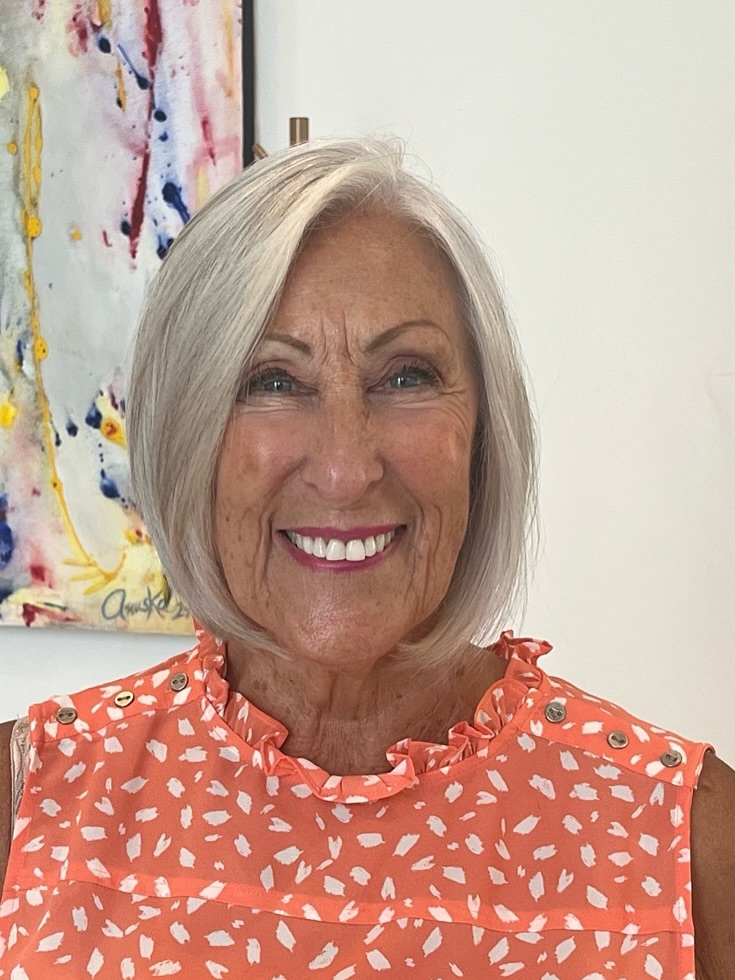 A woman with a sleek chin length platinum blonde angled bob hairstyle and a side part.