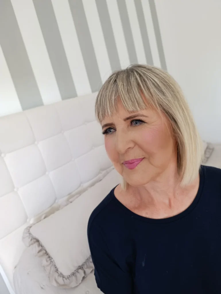 Straight blonde bob with blunt ends and full bangs.