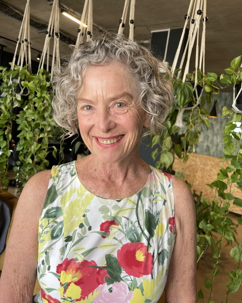 Short gray curly hairstyle with a soft rounded shape and natural texture.