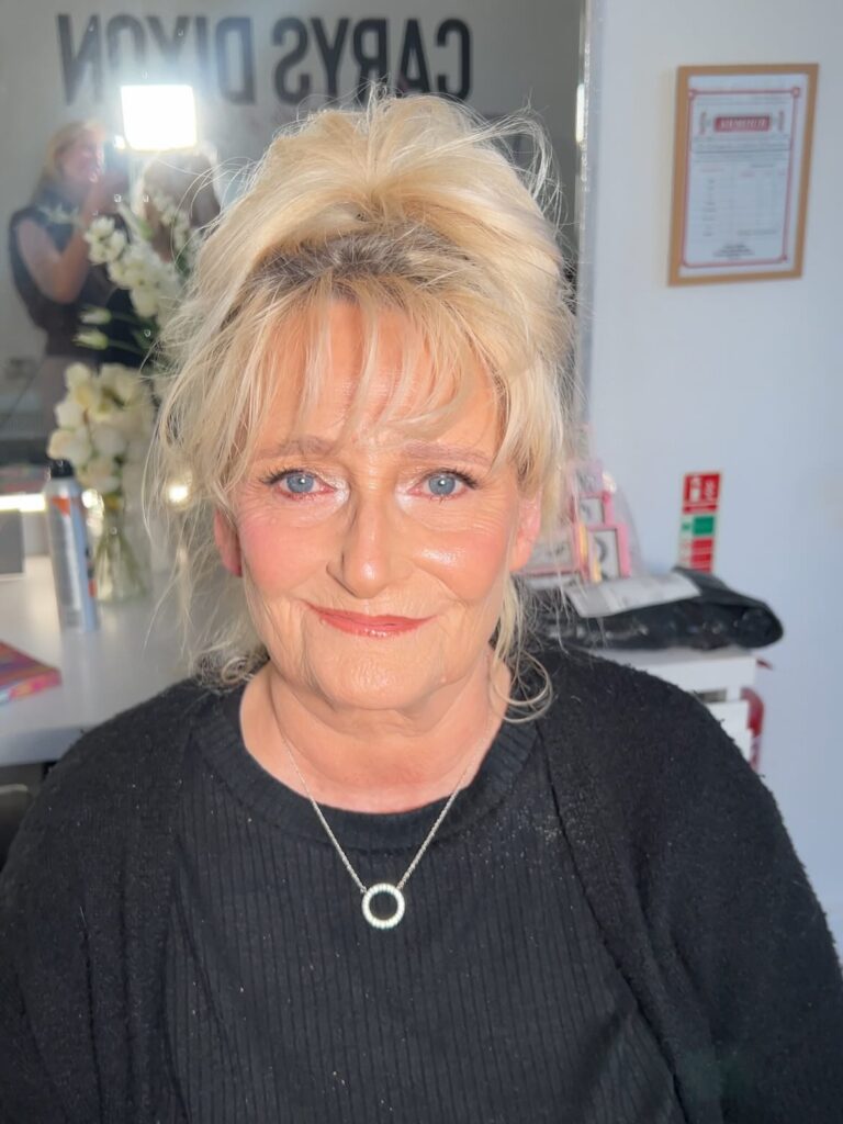 Blonde updo with soft wispy bangs and a relaxed, slightly tousled finish.