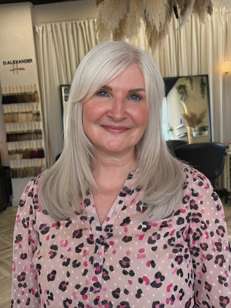 A woman with bright silver shoulder length hair styled with soft internal layers and flipped ends.