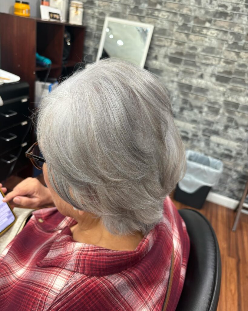 A woman with a short stacked silver bob featuring feathery layers and a voluminous back.