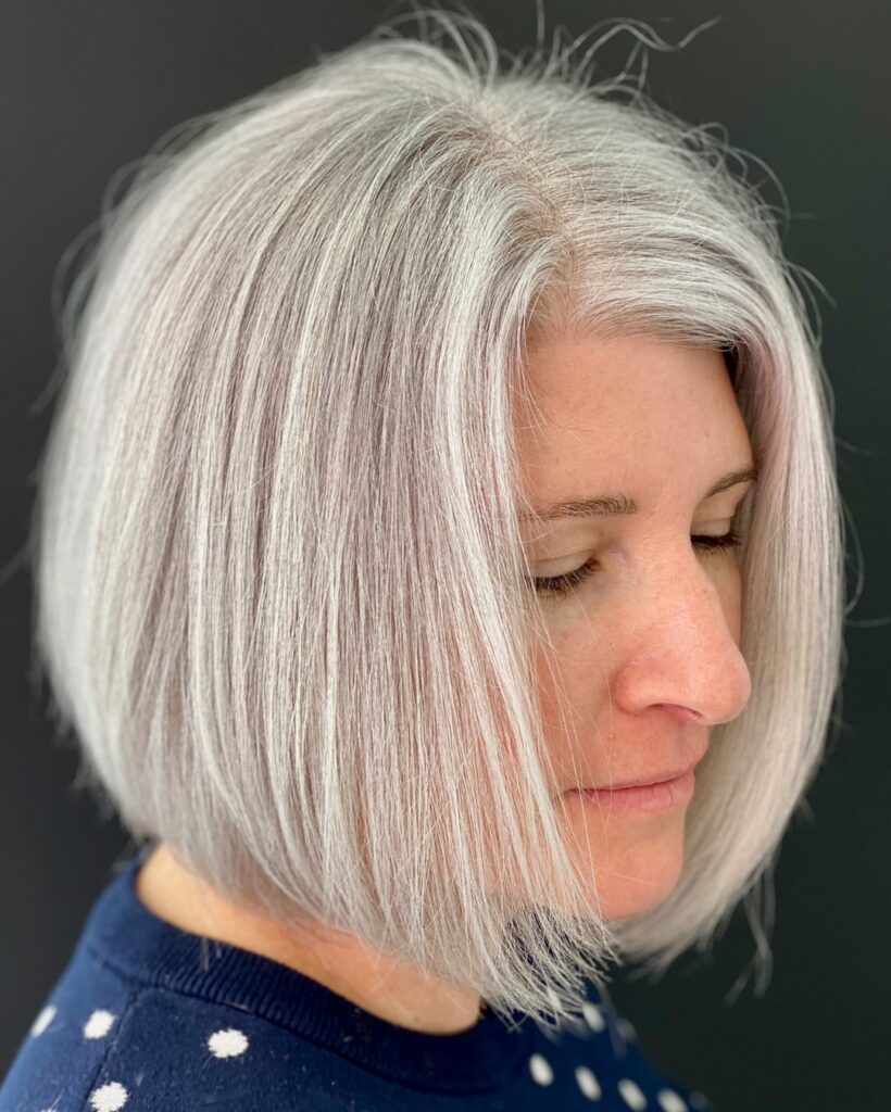 A woman with a sleek and straight angled bob in a natural bright white silver shade.