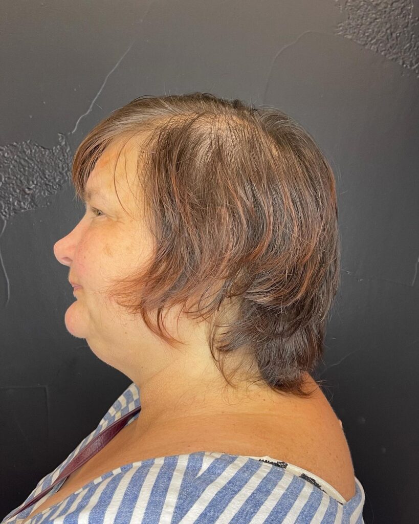 A woman with thick auburn and brunette hair styled in a feathered shag cut with soft wispy layers.
