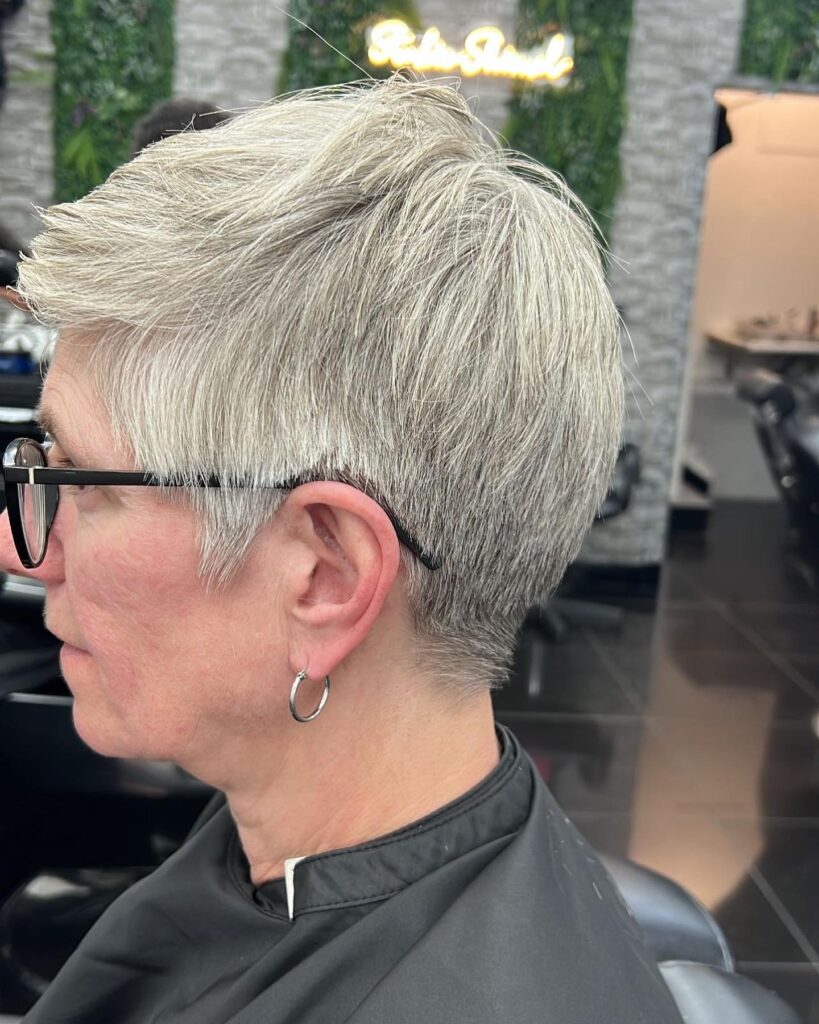 A woman with thick straight silver hair styled in a short tapered pixie cut with textured layers on top.
