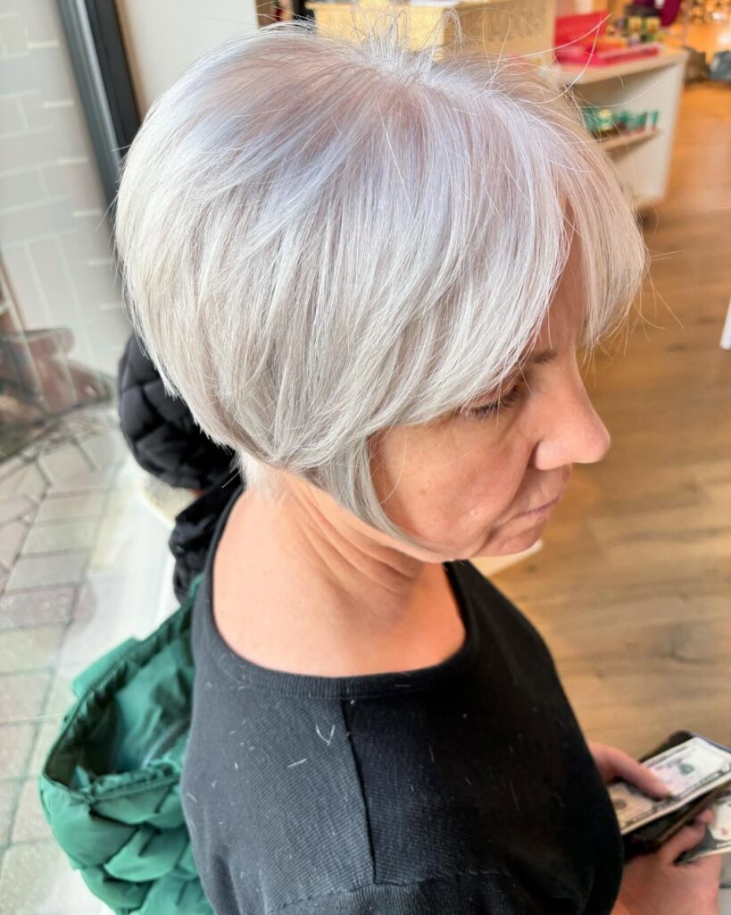 A woman with a short angled bob in a bright silver shade featuring a tapered back and longer face framing pieces.