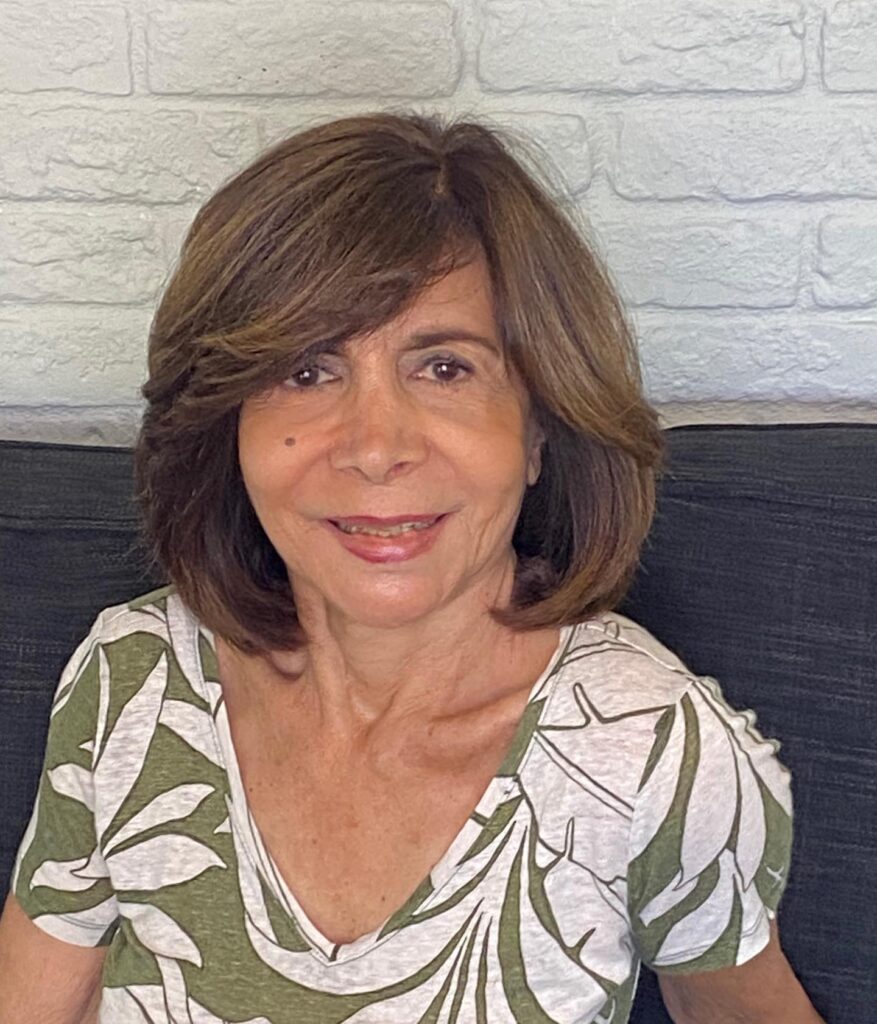 A woman with a voluminous shoulder length chestnut brown bob featuring layered ends and side swept bangs.