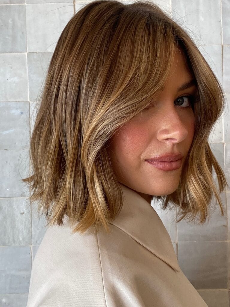 Medium length wavy lob with soft face framing layers and light brown tones.