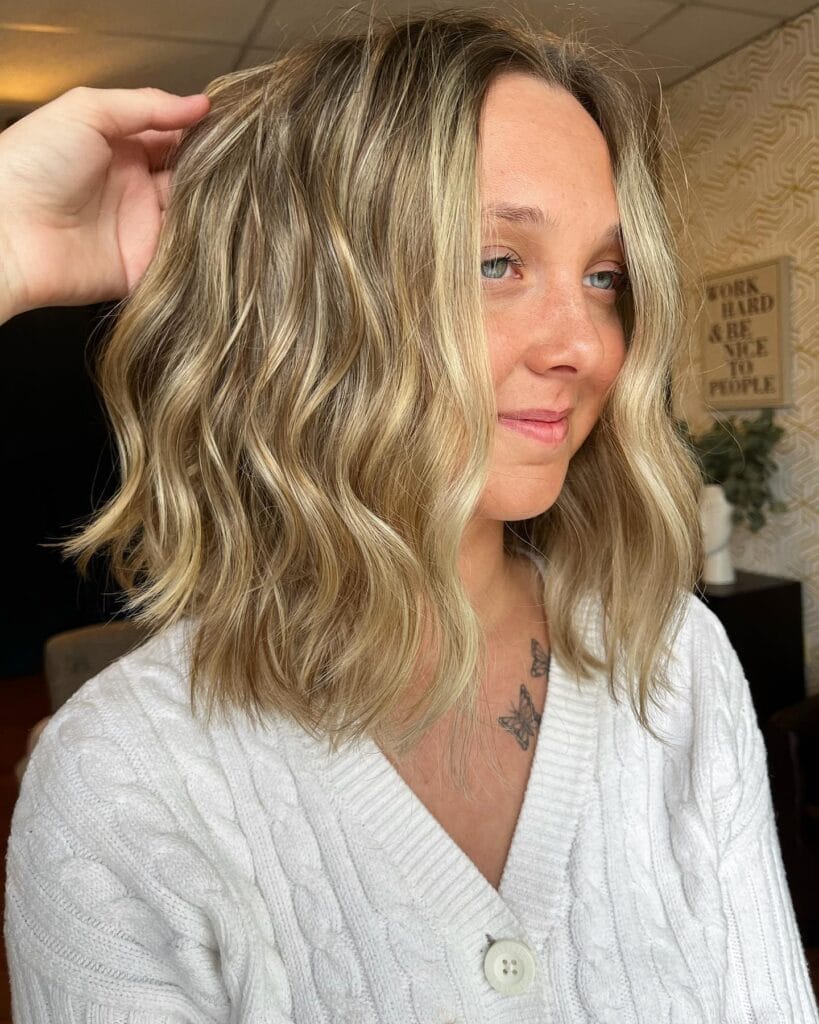 Medium length wavy hairstyle with blonde highlights and layered texture.