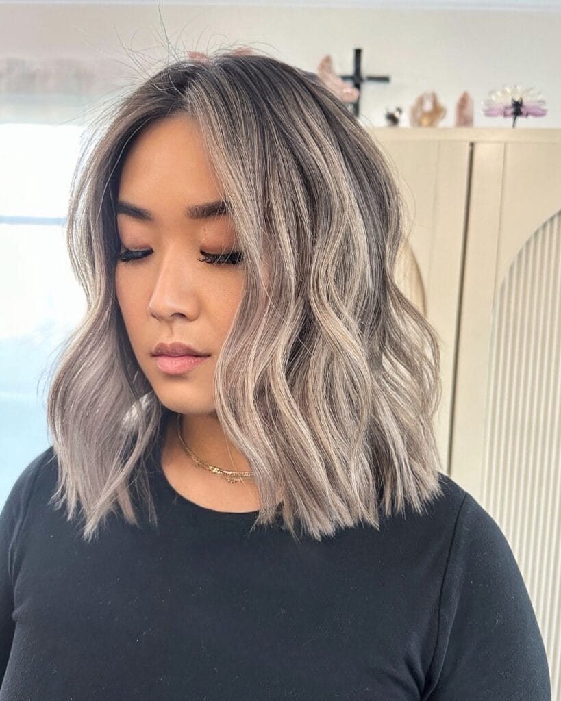 Medium length wavy lob with ash blonde highlights and textured beach waves.