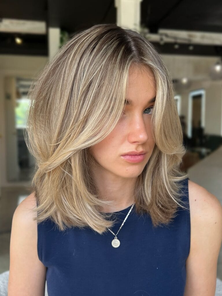 Medium length blonde layered hairstyle with soft face framing layers.