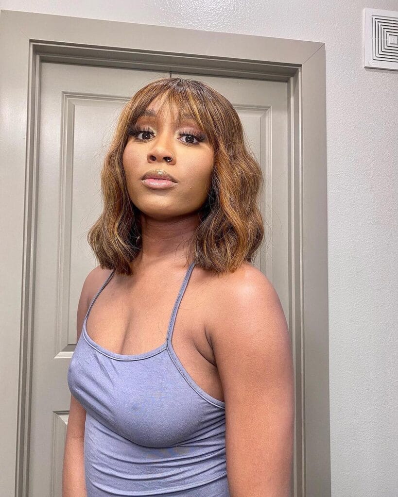 Shoulder length wavy bob with soft bangs and warm brown tones.