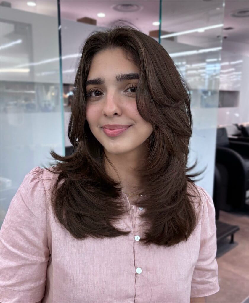 Medium length brunette layered hairstyle with soft flipped ends and smooth texture.