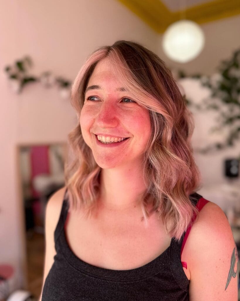 Shoulder length wavy hairstyle with soft rosy blonde tones and natural texture.