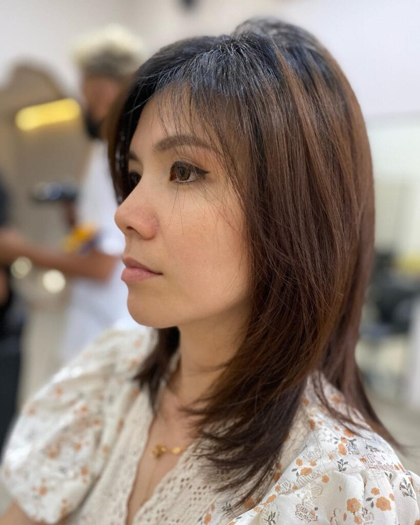 Medium length dark brown layered hairstyle with feathered ends and soft volume.