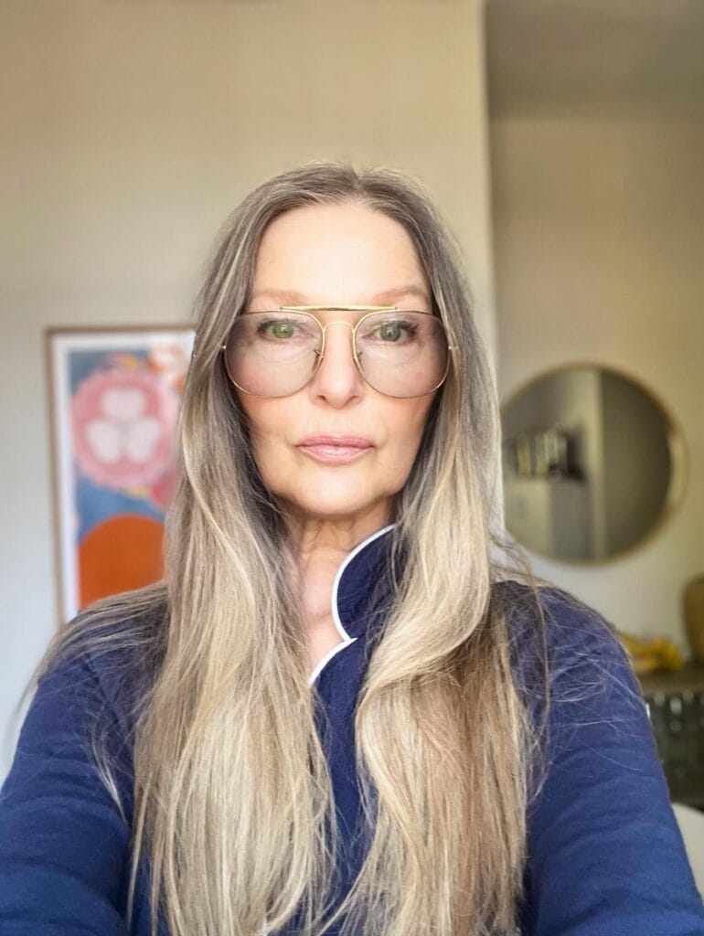 A woman with long straight blonde hair styled with a center part and smooth finish.