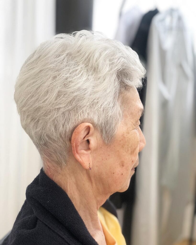 A woman with a short white pixie haircut styled with feathered layers and light volume.