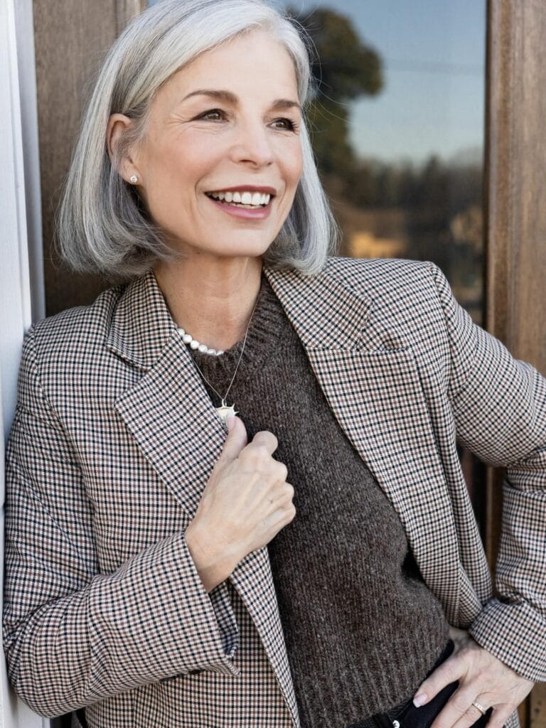 A woman with a chin length gray bob styled with a side part and softly tucked ends.