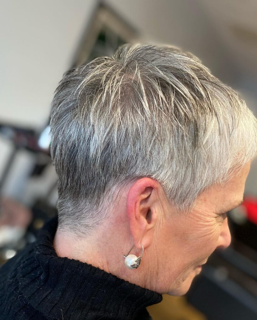 A woman with a short silver pixie haircut styled with soft layers and a clean finish.