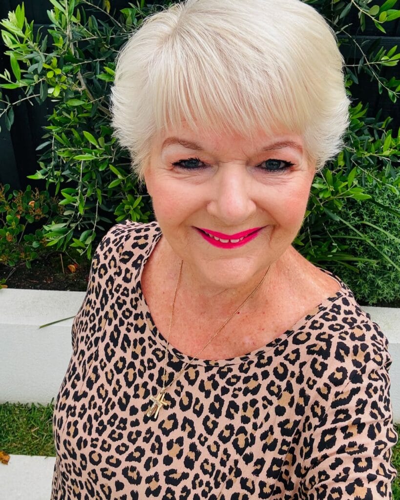 Rounded blonde pixie haircut with soft layers and a light full fringe.