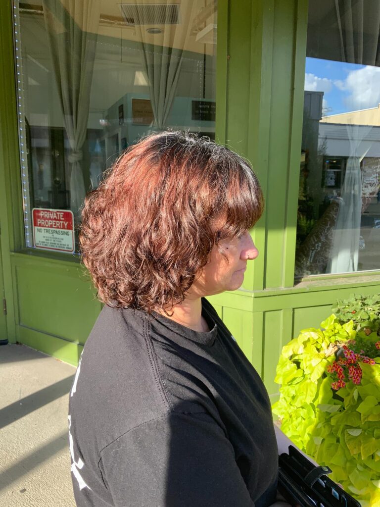 A woman with thick wavy auburn hair styled in a layered bob with bangs.