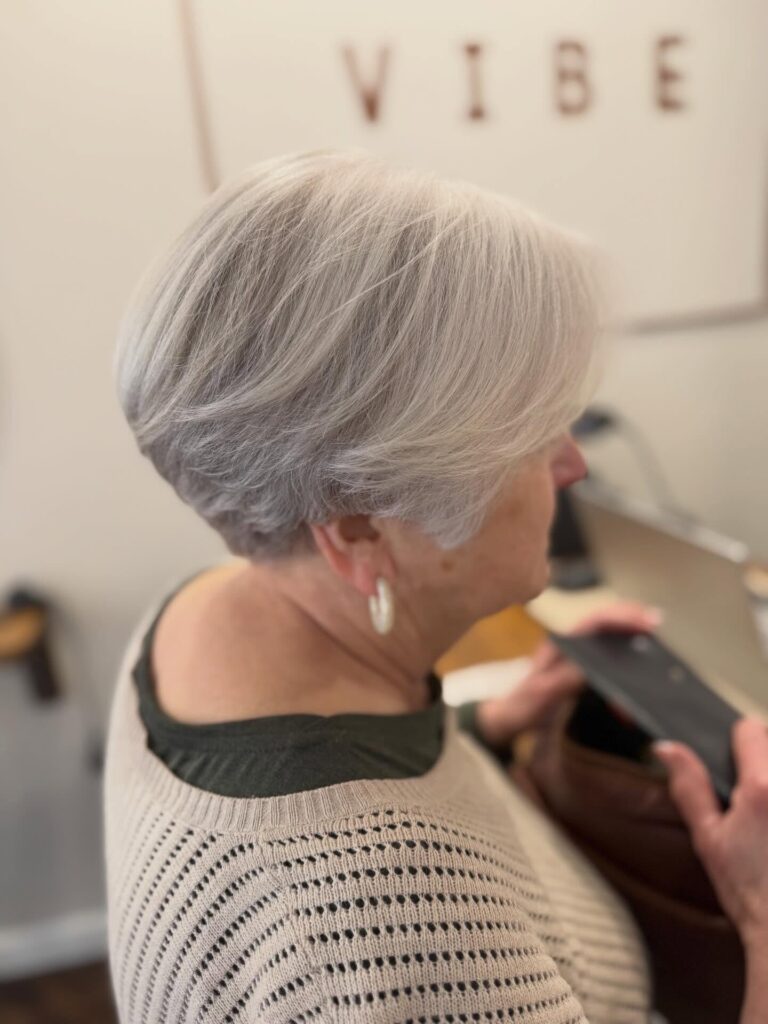 A woman with thick short silver hair styled in a tapered pixie cut with side swept layers.