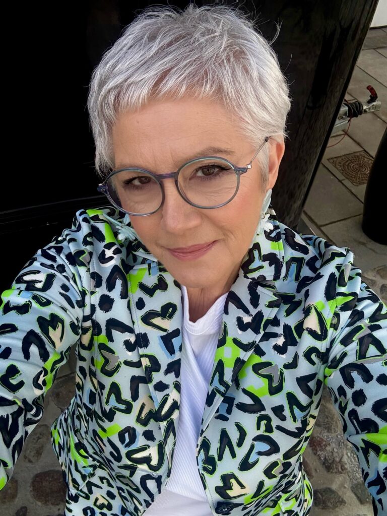 Short silver pixie haircut with soft texture styled with glasses.