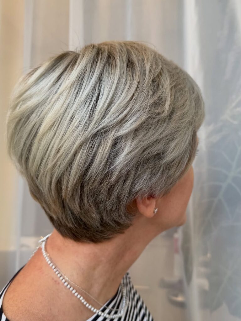 Short silver pixie haircut with soft layers and a smooth finish.