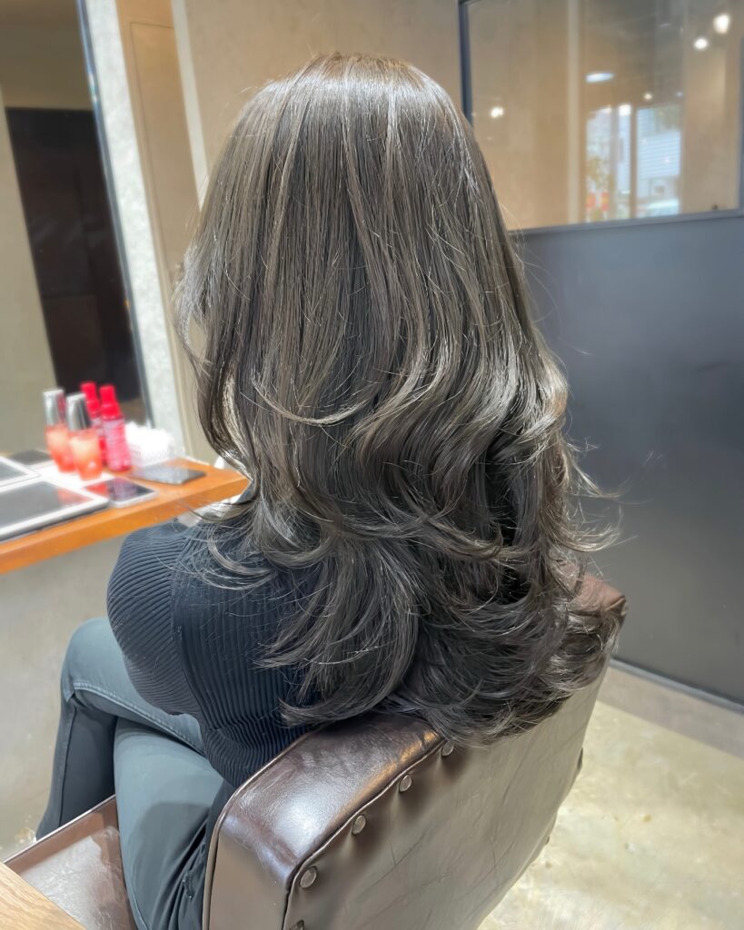 Long layered black hair with feathered ends and soft curled volume.