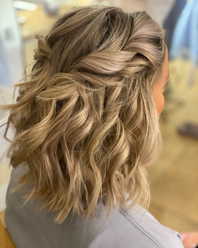 Medium blonde balayage hair with beach waves and a twisted half up hairstyle.