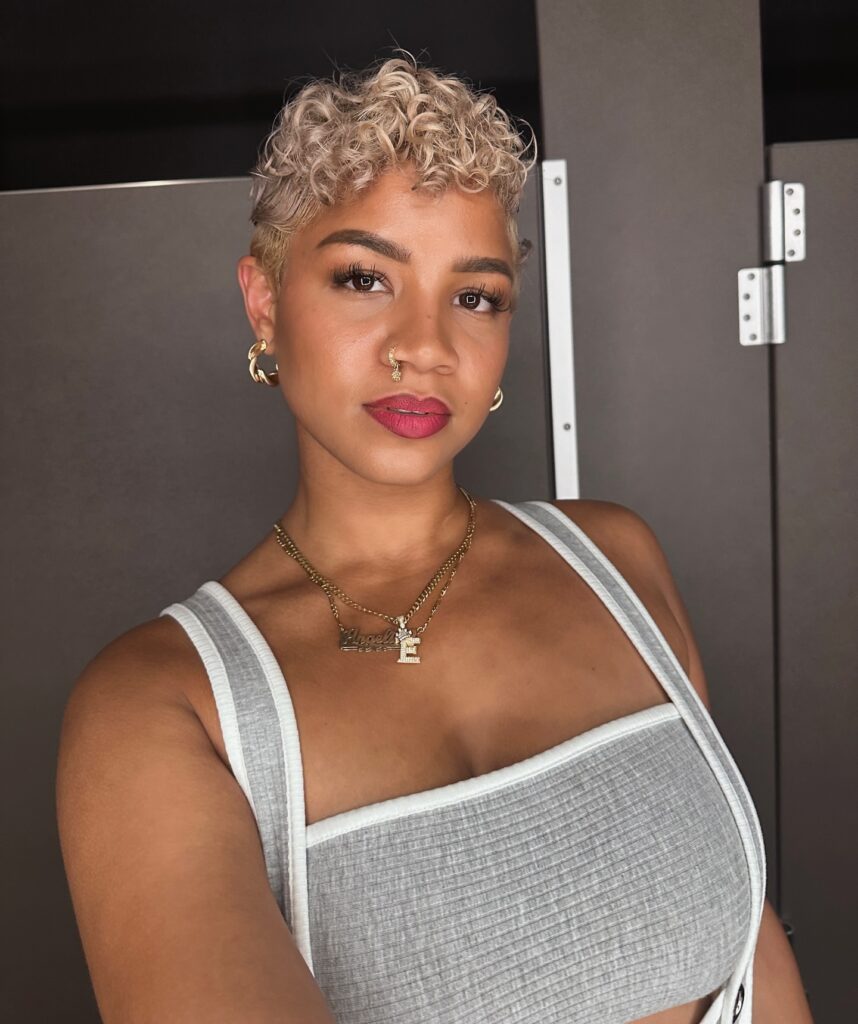Short platinum blonde curly pixie cut with tight curls and a soft shape.