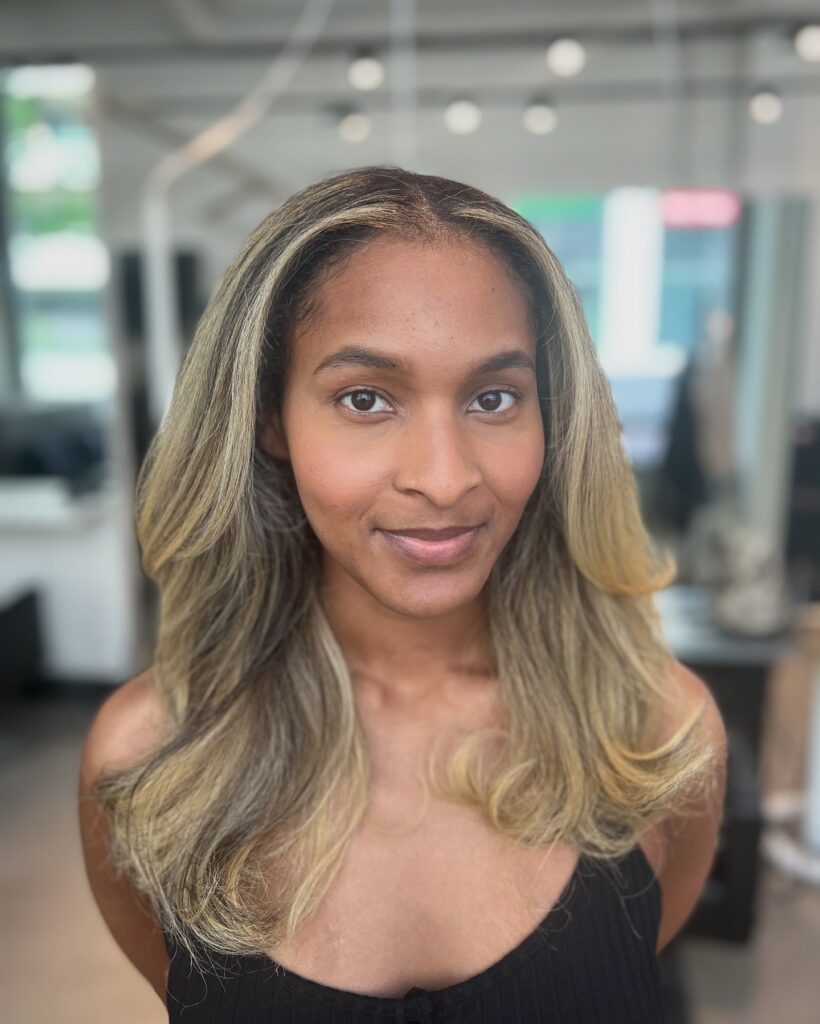 Medium length ash blonde hair with soft layers and a smooth blowout finish.