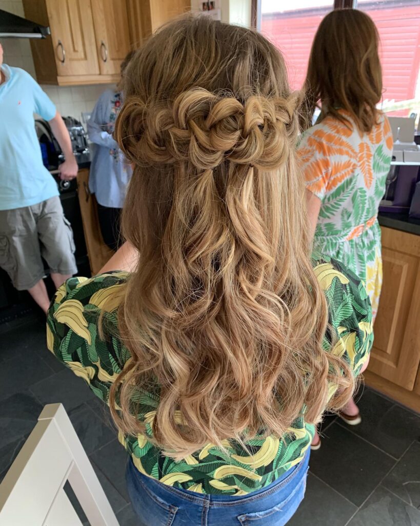 Long wavy blonde hair with a twisted crown braid detail at the back.