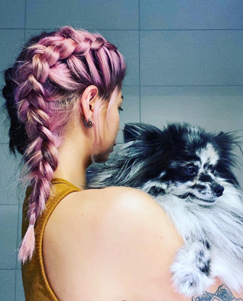 Pastel pink hair styled into two braids with a slightly messy texture.