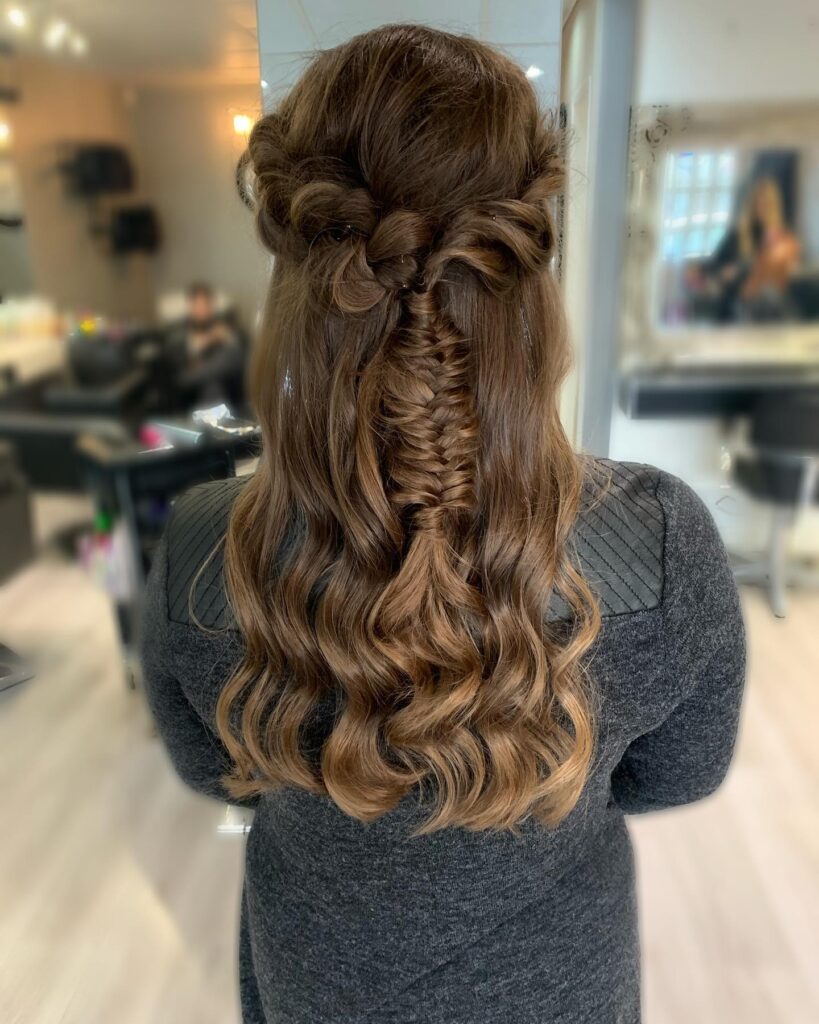 Brown hair styled in a half up fishtail braid with loose curls underneath.