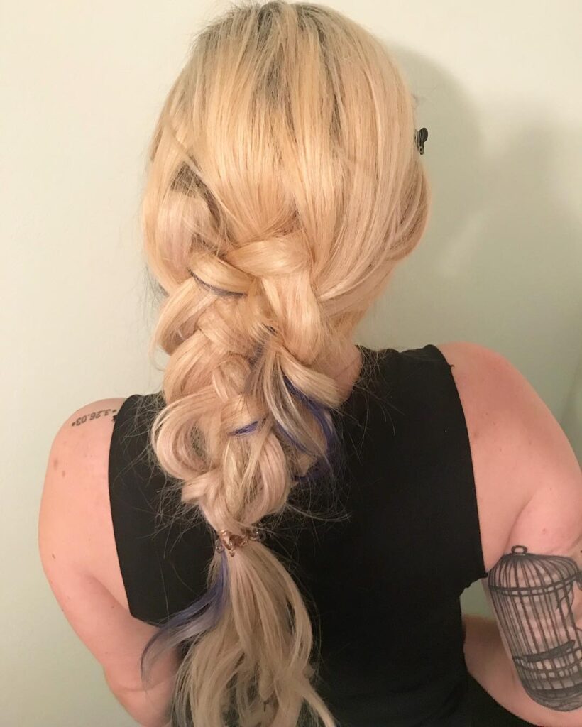 Loose blonde braid with soft volume and subtle colored strands peeking through.