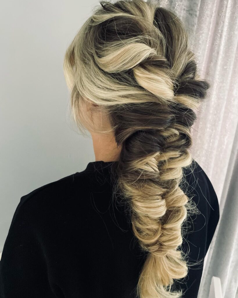 Thick loose braid with dark roots and blonde highlights creating a bold contrast.