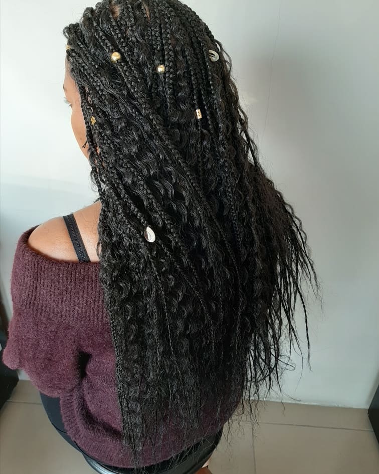 Long black box braids mixed with loose wavy hair and decorated with beads and shells.