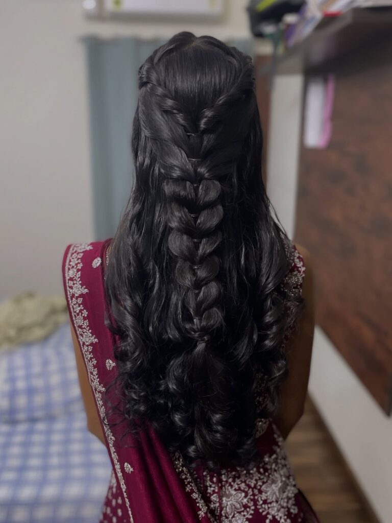 Long black wavy hair styled with a loose pull through braid down the back.