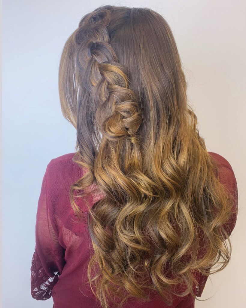 Long wavy balayage hair with a loose side braid along the crown.