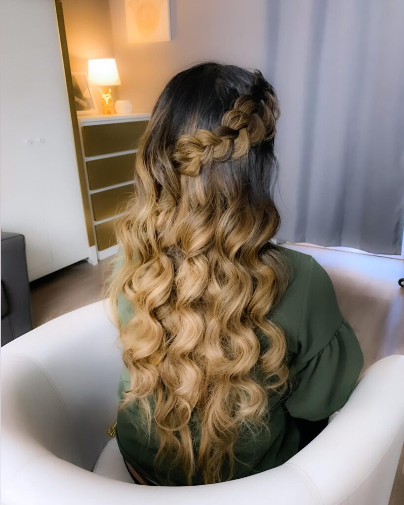 Half up hairstyle with a side braid and long loose wavy hair.