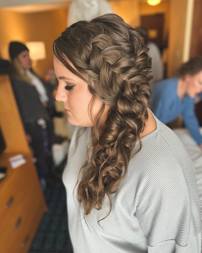 Long brunette hair styled into a thick side braid with curled ends.