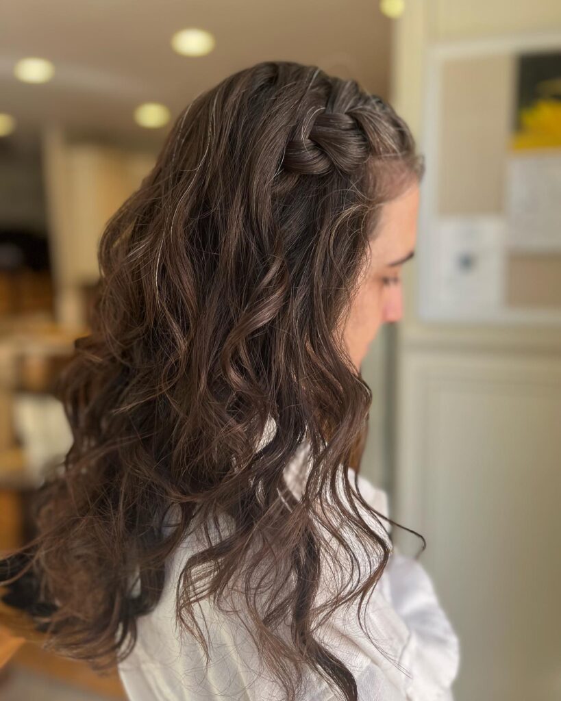 Long wavy brown hair with a subtle side braid along the front.