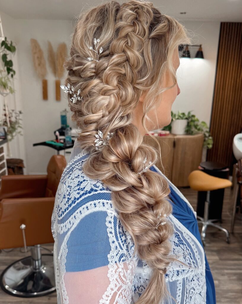 Blonde textured side braid with soft volume and decorative hair pins.
