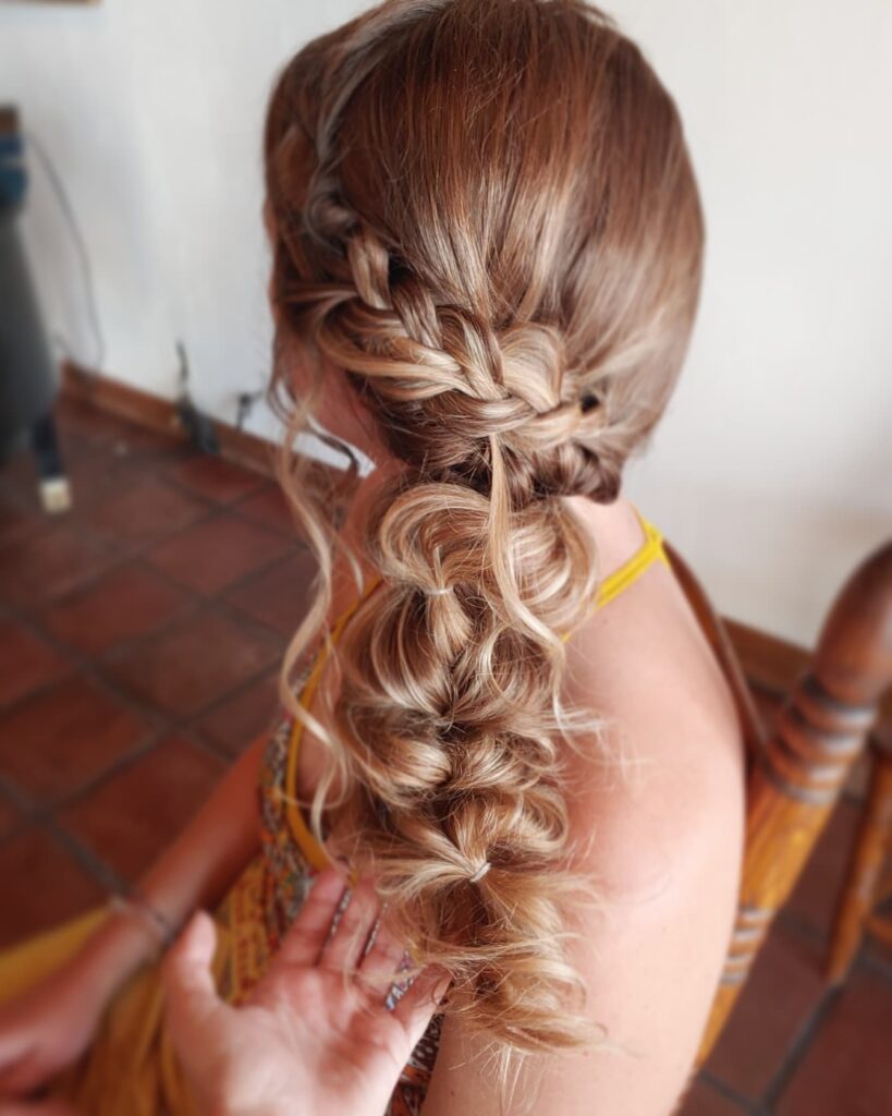 Blonde hair styled in a loose side braid with soft curled ends.
