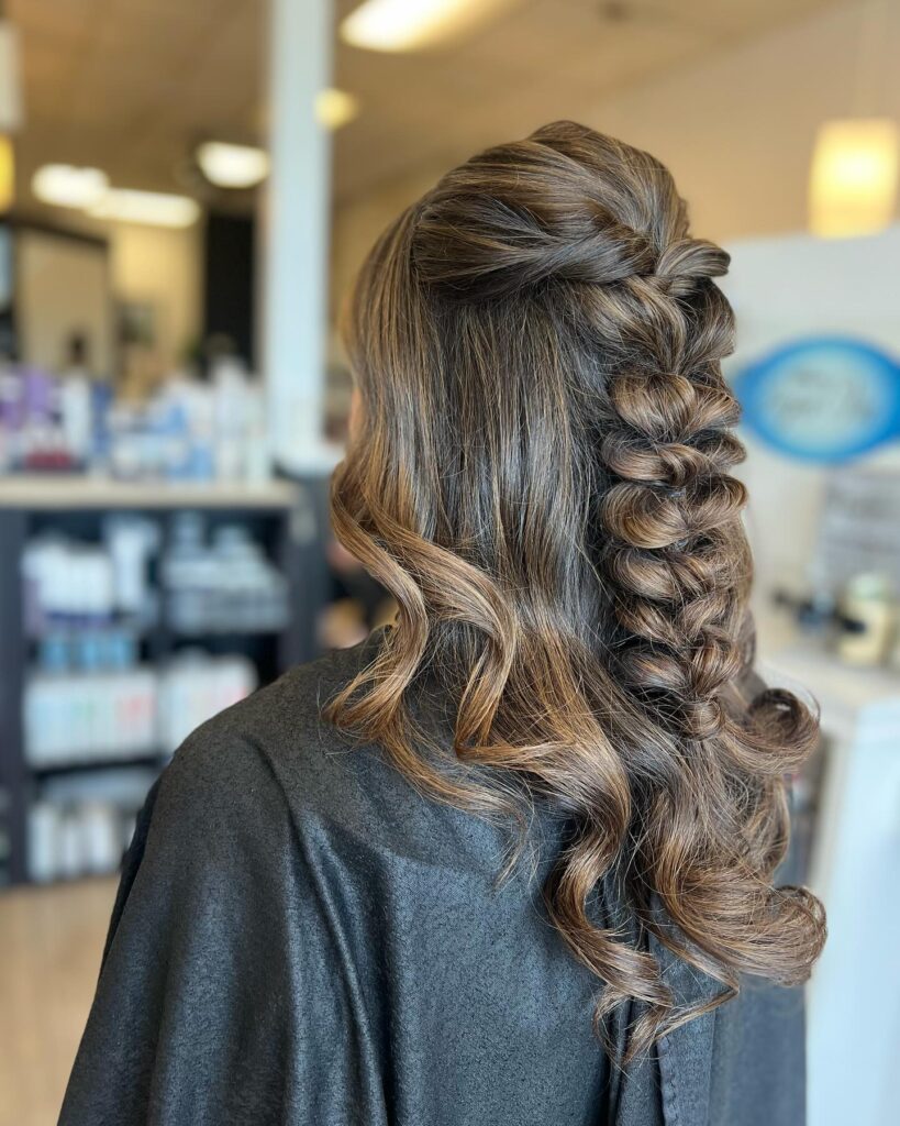 A half up bubble braid with soft curled ends on medium length brown hair.
