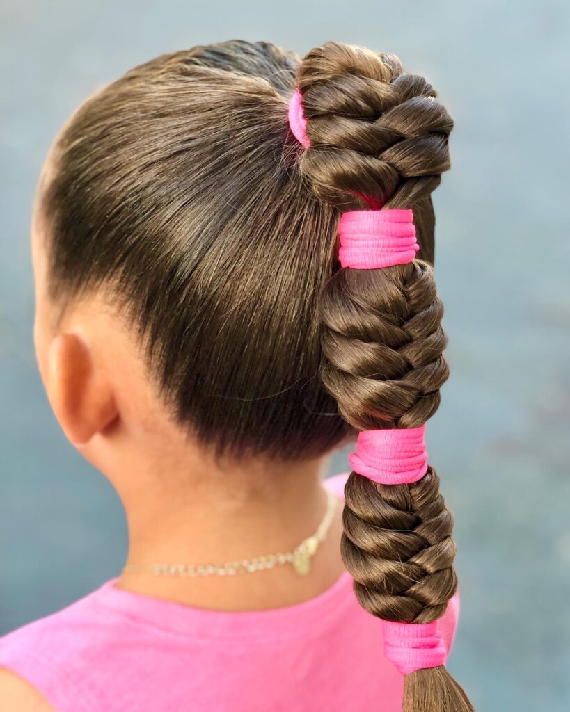 A high ponytail bubble braid with small sections secured by pink bands.