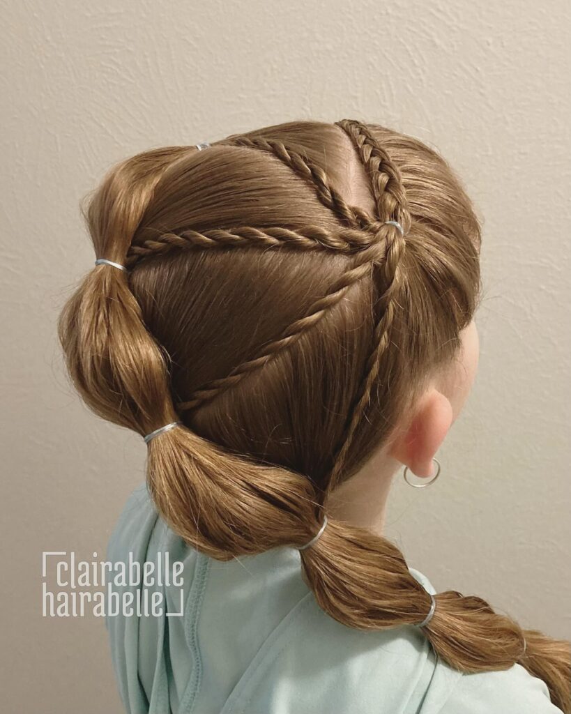 A criss cross braided style that leads into a low bubble ponytail on light brown hair.