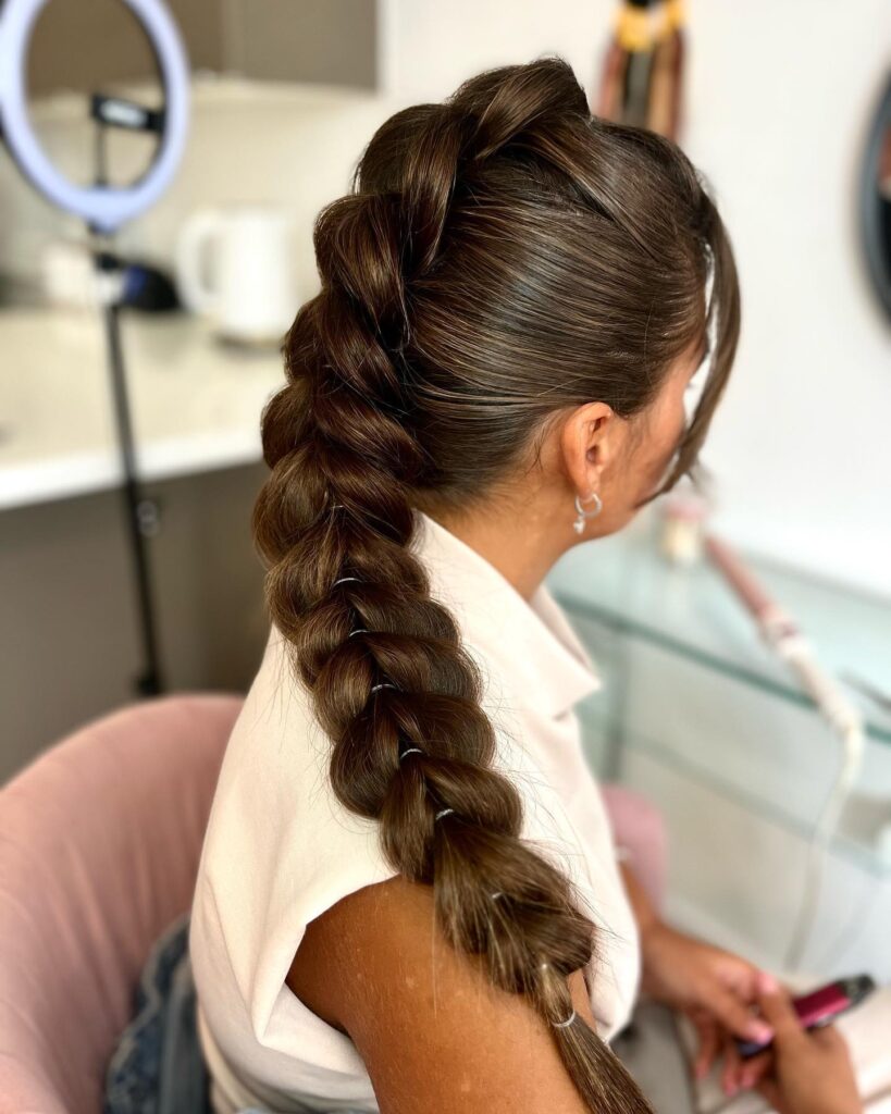 A sleek low ponytail styled into a bubble braid with evenly spaced sections on dark brown hair.
