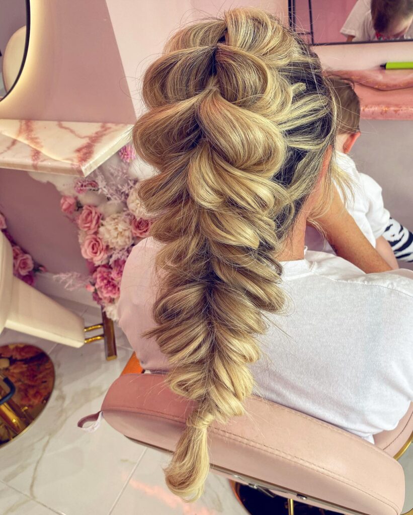 A textured blonde bubble braid with voluminous pulled apart sections down the back.